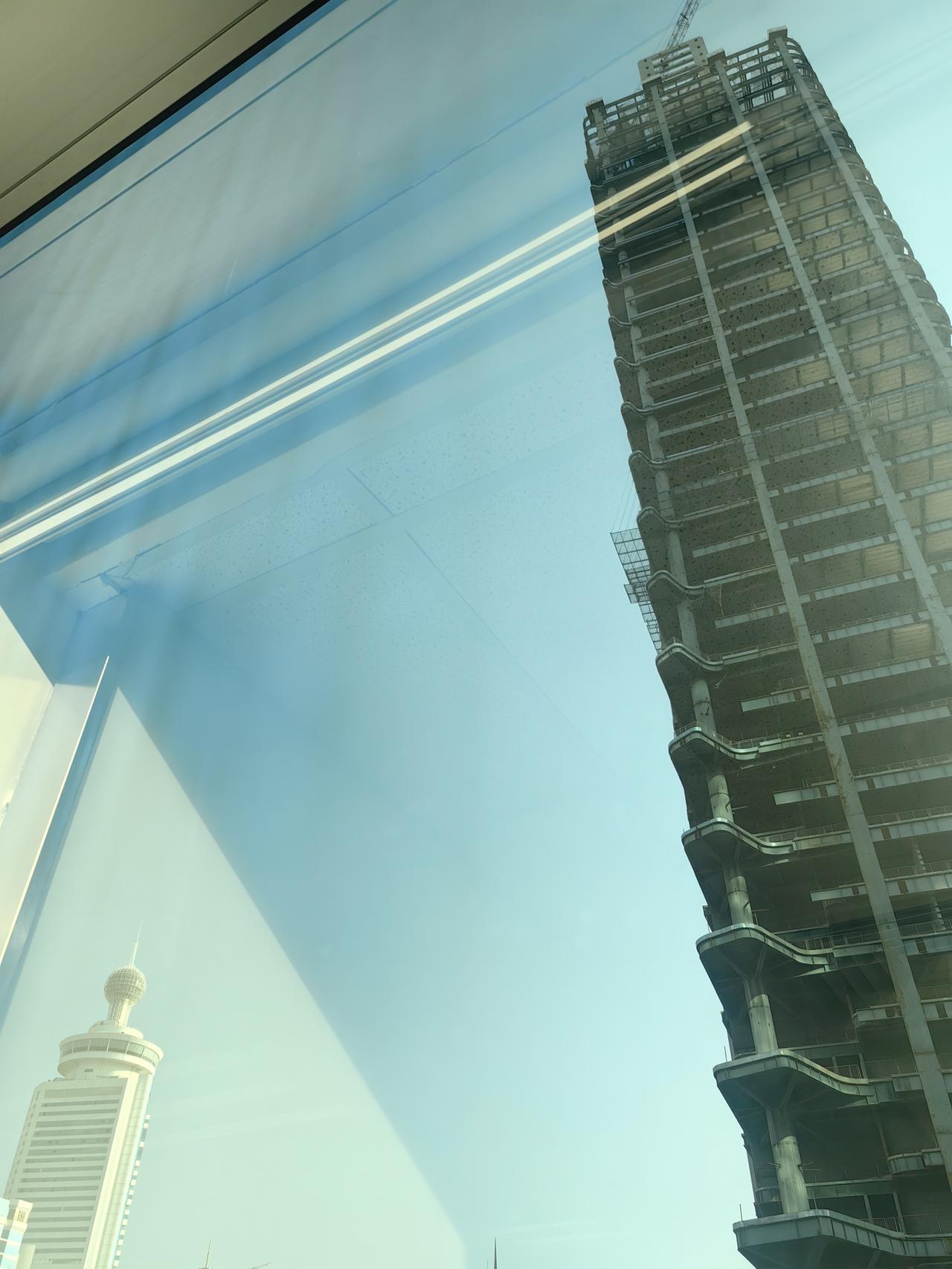 隔壁的金光华广场人流如织，仅有一楼之隔这座大楼，为什么就烂尾了呢？远处的彭年酒店