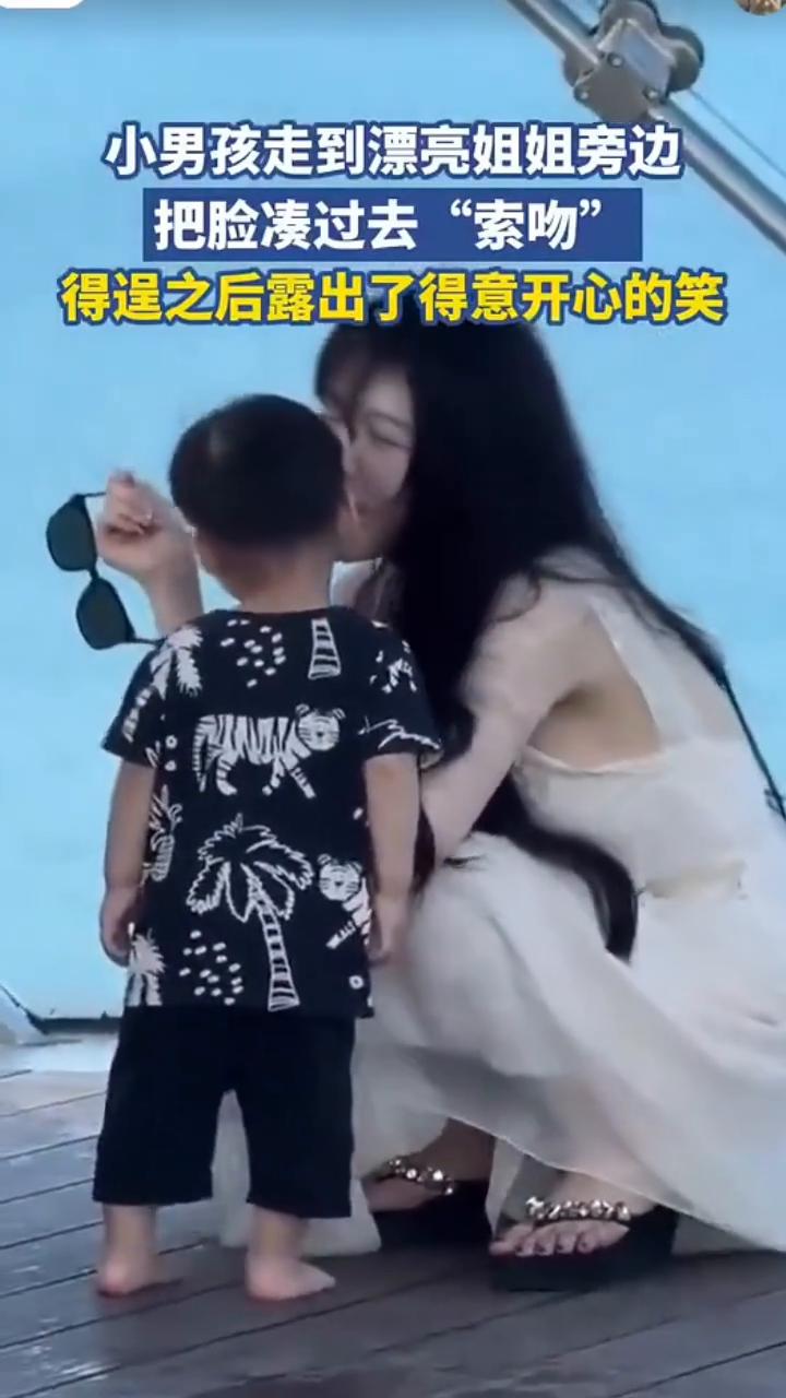 小男孩走到漂亮姐姐旁边，把脸凑过去"索吻"，得逞之后露出了得意开心的笑。
6月6