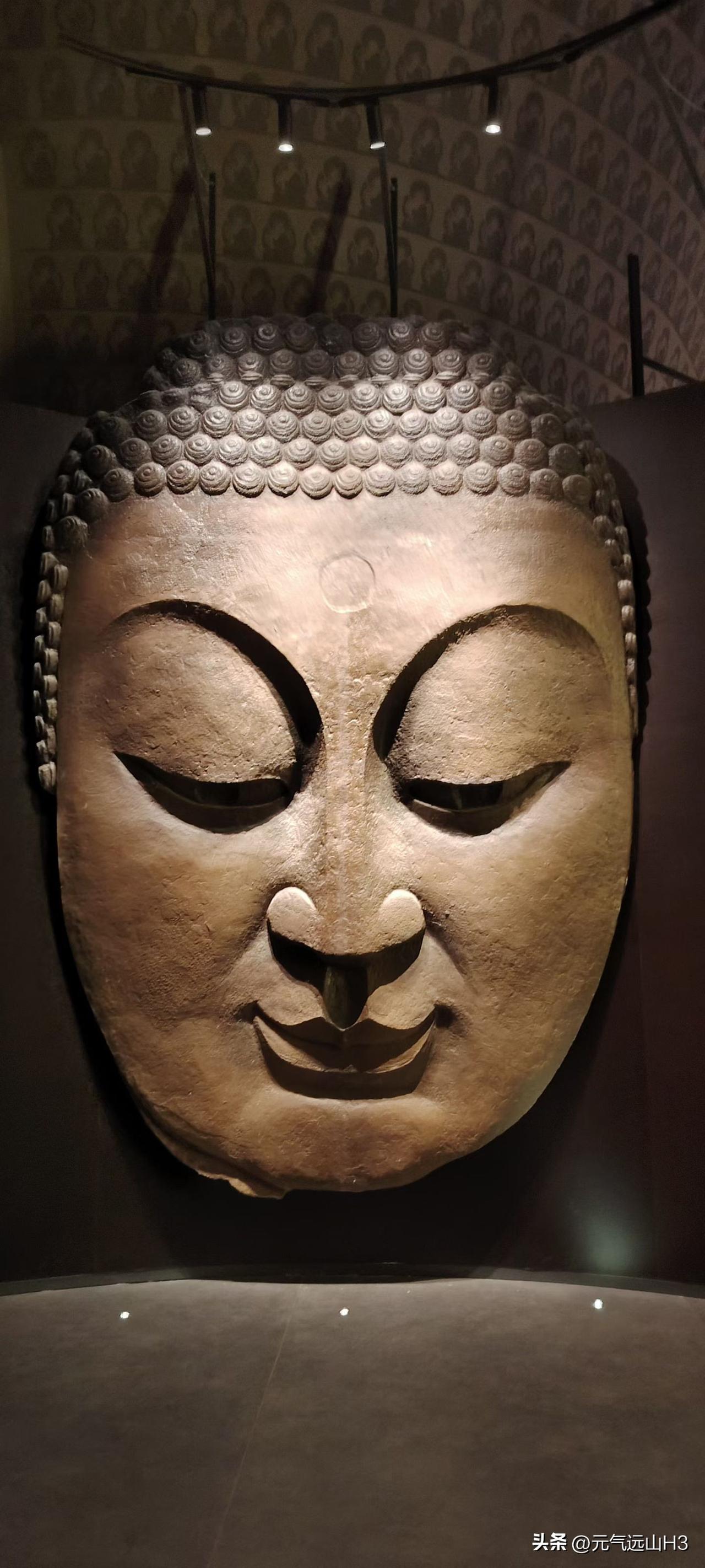 这尊佛首，以石为骨，以静为魂。螺髻细密如星，额间白毫隐现，眼睑轻垂间，似含万象慈