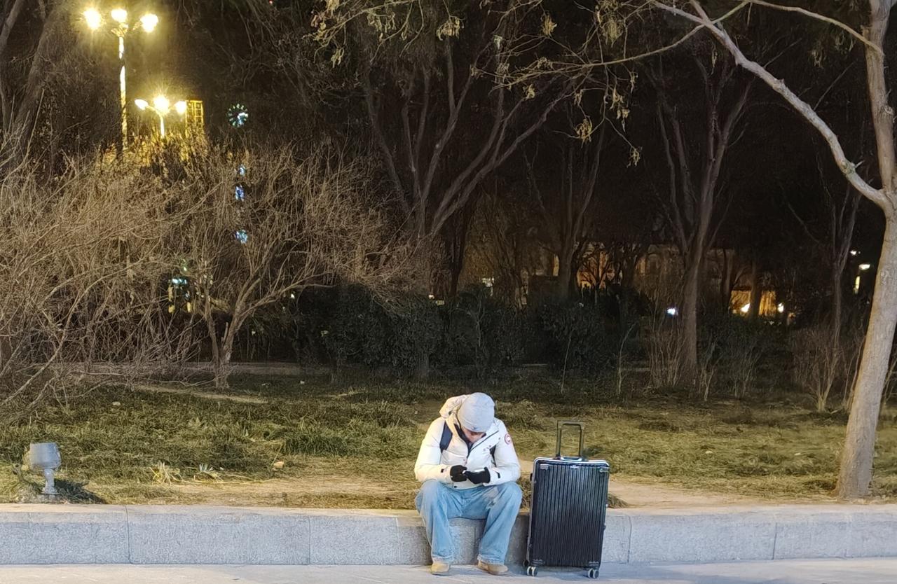 大冷天在天津站津湾广场的路边，有个小伙在那全神贯注打游戏，玩得那叫一个津津有味。