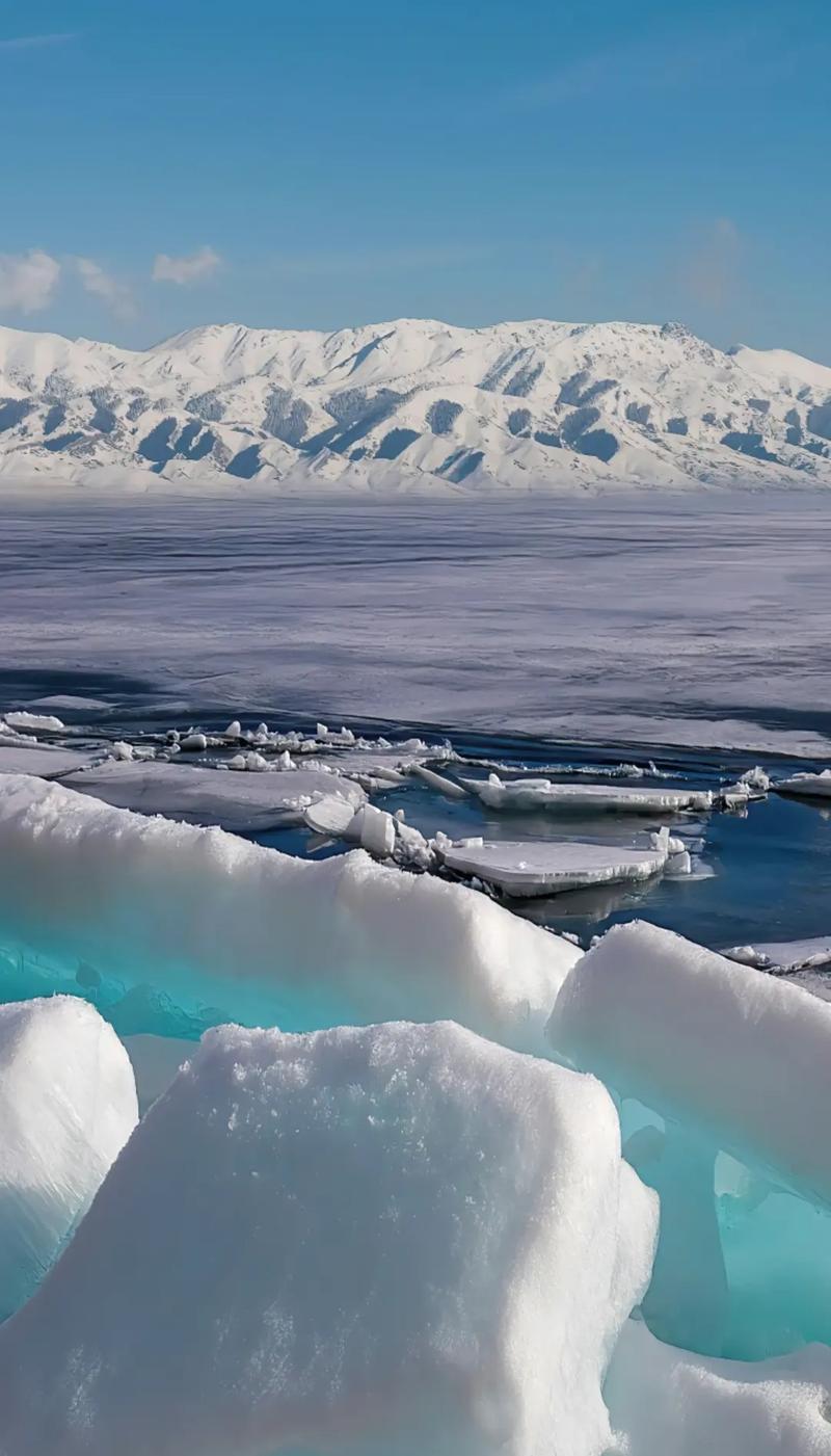 极地冰川的壮丽景象，冰山漂浮在湛蓝的海面上，远处的雪山与蓝天相映成趣。