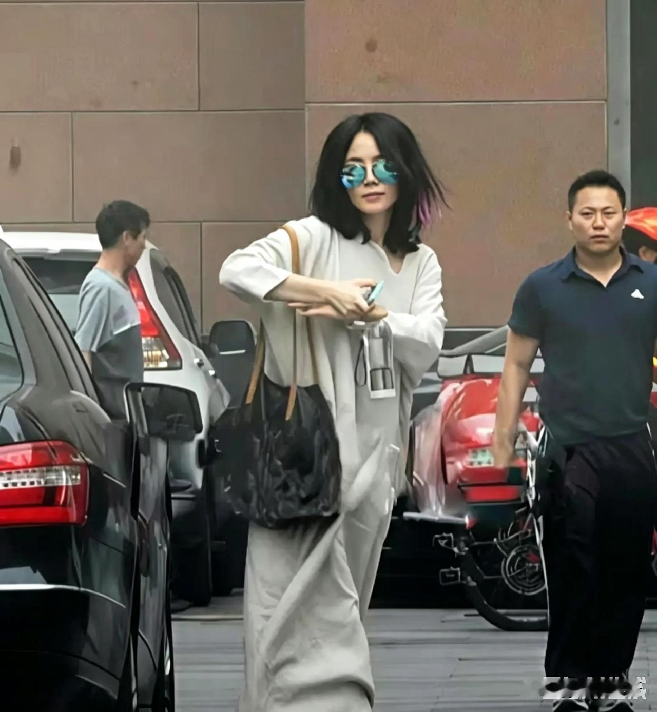 街头抓拍的画面里，王菲一身宽松素色休闲套装，戴着炫彩墨镜，挎着大包，步履随性，自