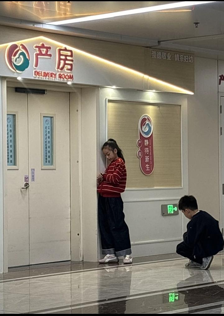 老婆生宝宝进产房后，大人都在远处椅子上坐着，两个孩子一直守在产房门口。她们是老婆