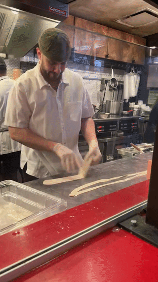 美国一家中餐厅里。
一个老然正在制作“正宗河南烩面”？
瞧他扯面的手法。
看起来