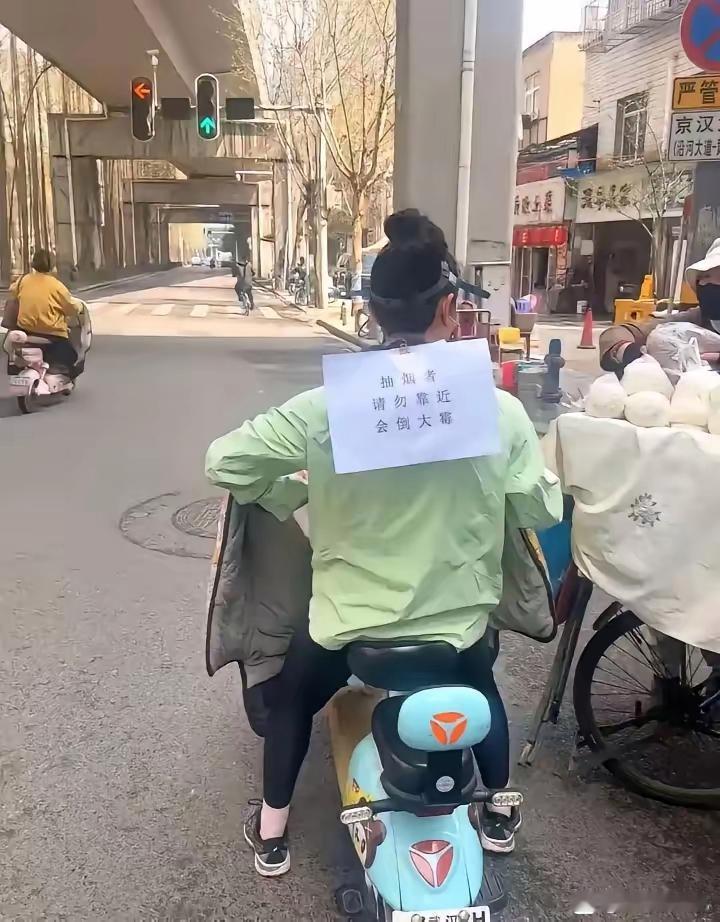 大街上看到一位女土 骑着一辆电动车只见这位女土衣服后面贴着一张白纸 她为什么要这