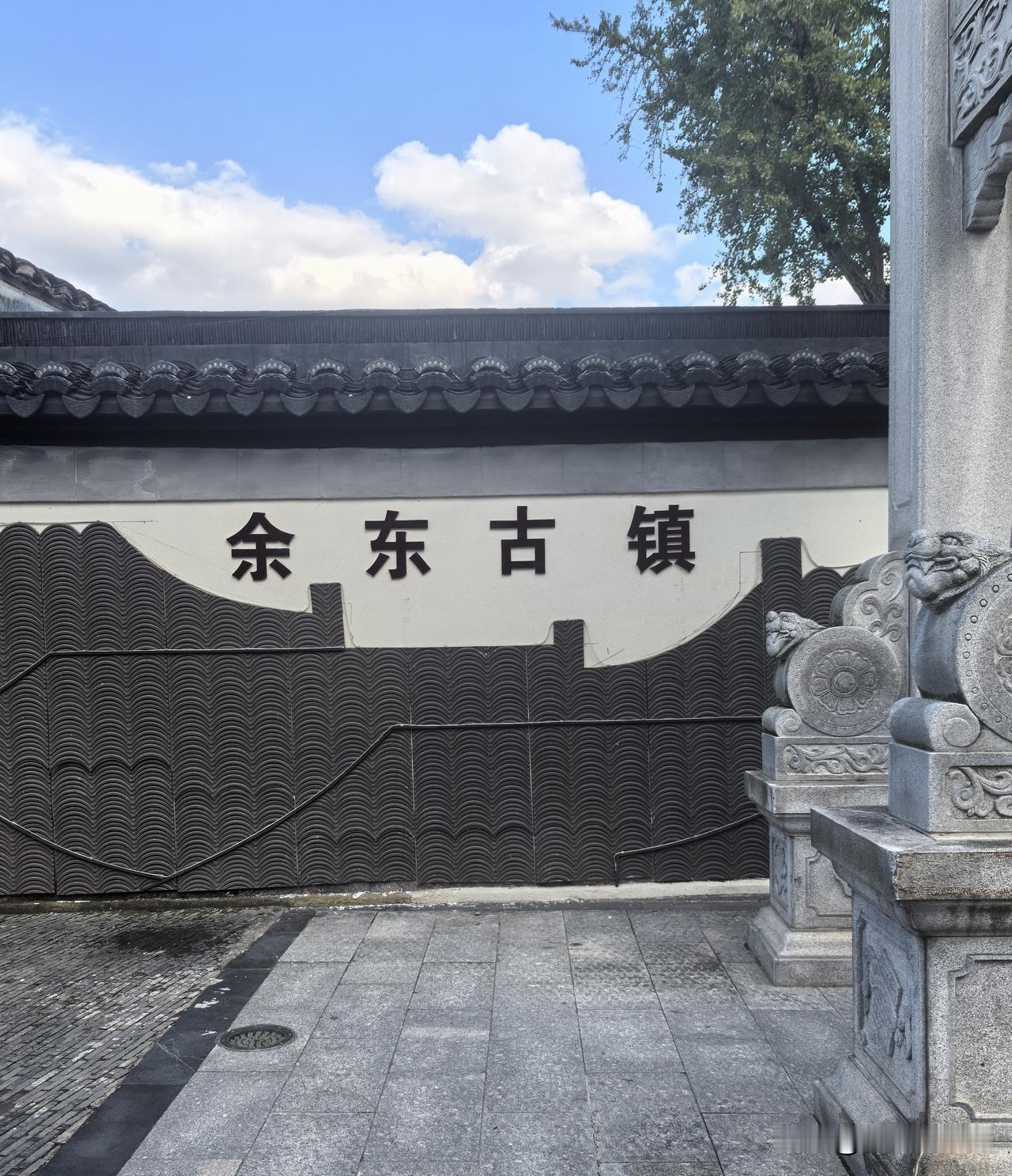 黑瓦白墙的特色照壁上，“余东古镇”几个大字古朴厚重；旁边石狮子静静伫立，满含江南