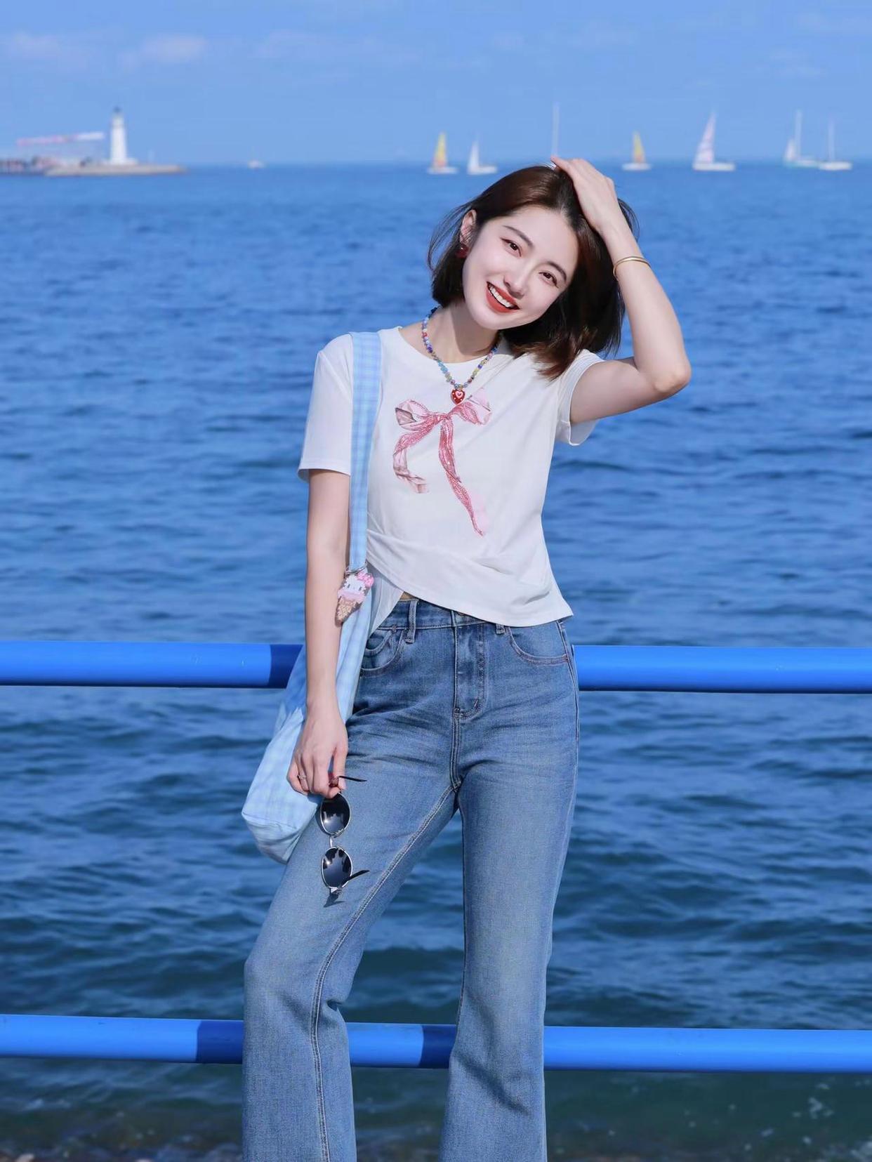 海天一色漫开清蓝，牛仔衬得身姿轻盈，女孩一笑，便揉碎整片海面的温柔星光
