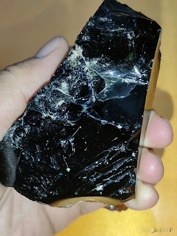 江边寻获熔融碎块一枚，通体覆盖黑色熔融外壳，具备清晰的熔融断口纹理。强光手电透射
