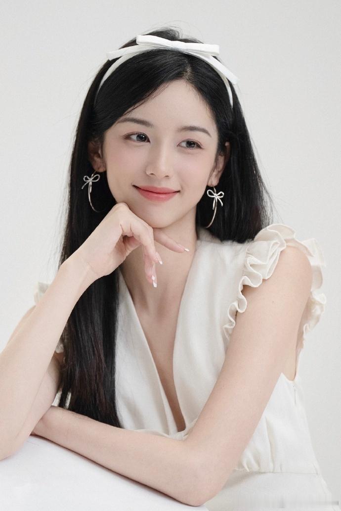 周也戴蝴蝶结发箍穿白色无袖花苞裙，举手投足间满是优雅与甜美，妥妥的氛围感女神！周