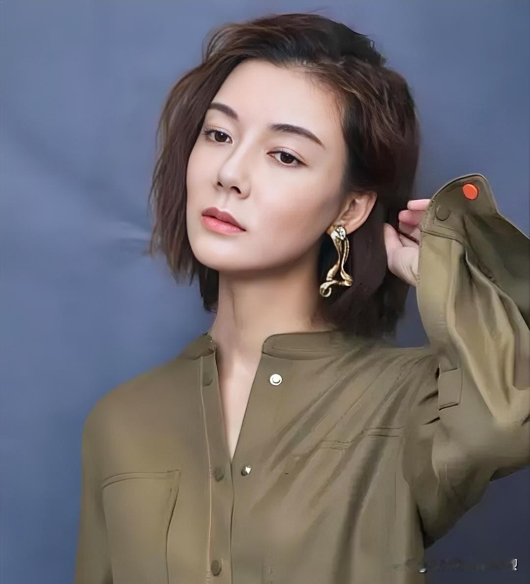 墨发微扬，金饰点睛，深蓝底色上孤傲如画。

军绿衣袂裹挟从容气度，指抚鬓边，冷艳