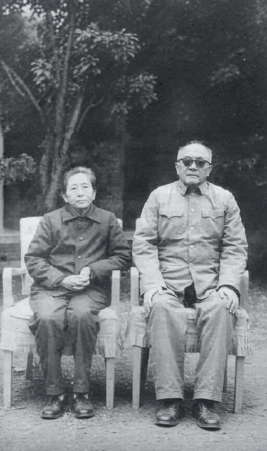 这张黑白旧照是晚年黄克诚大将与夫人唐棣华的庭院留影。二人端坐于木椅之上，衣着朴素