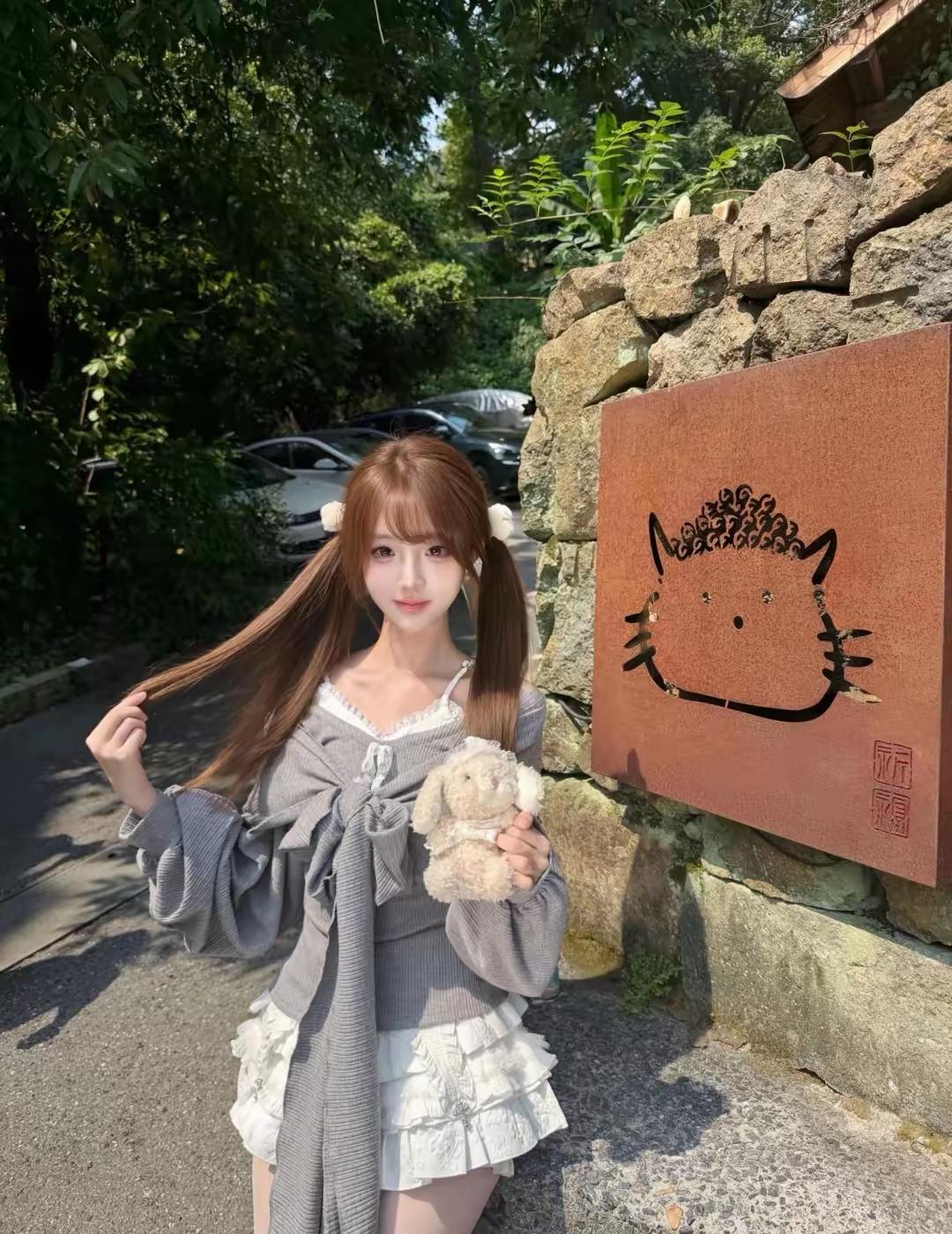 女孩在路边拿着玩偶拍照。