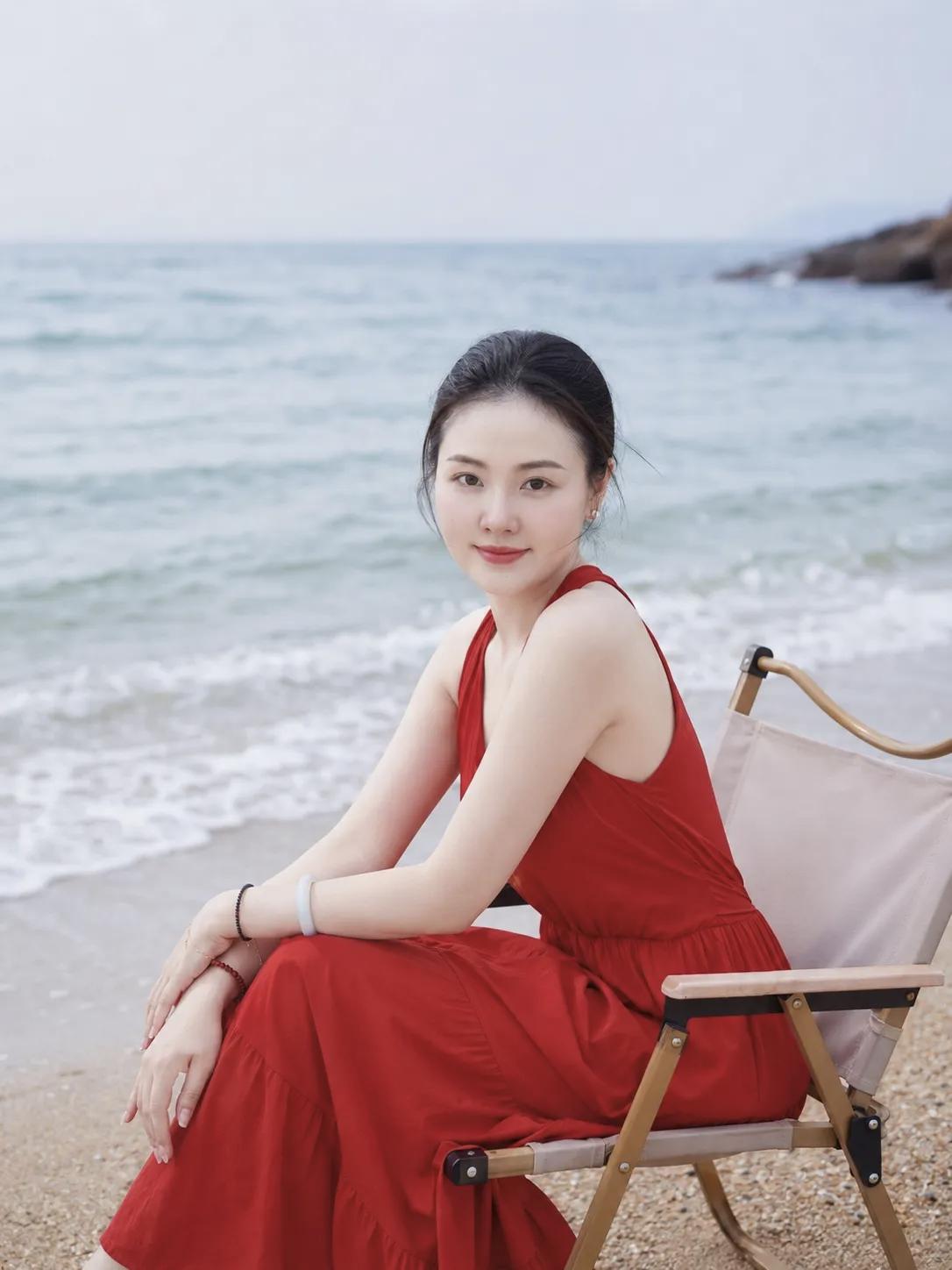 一个穿红裙子的女生坐在海边。