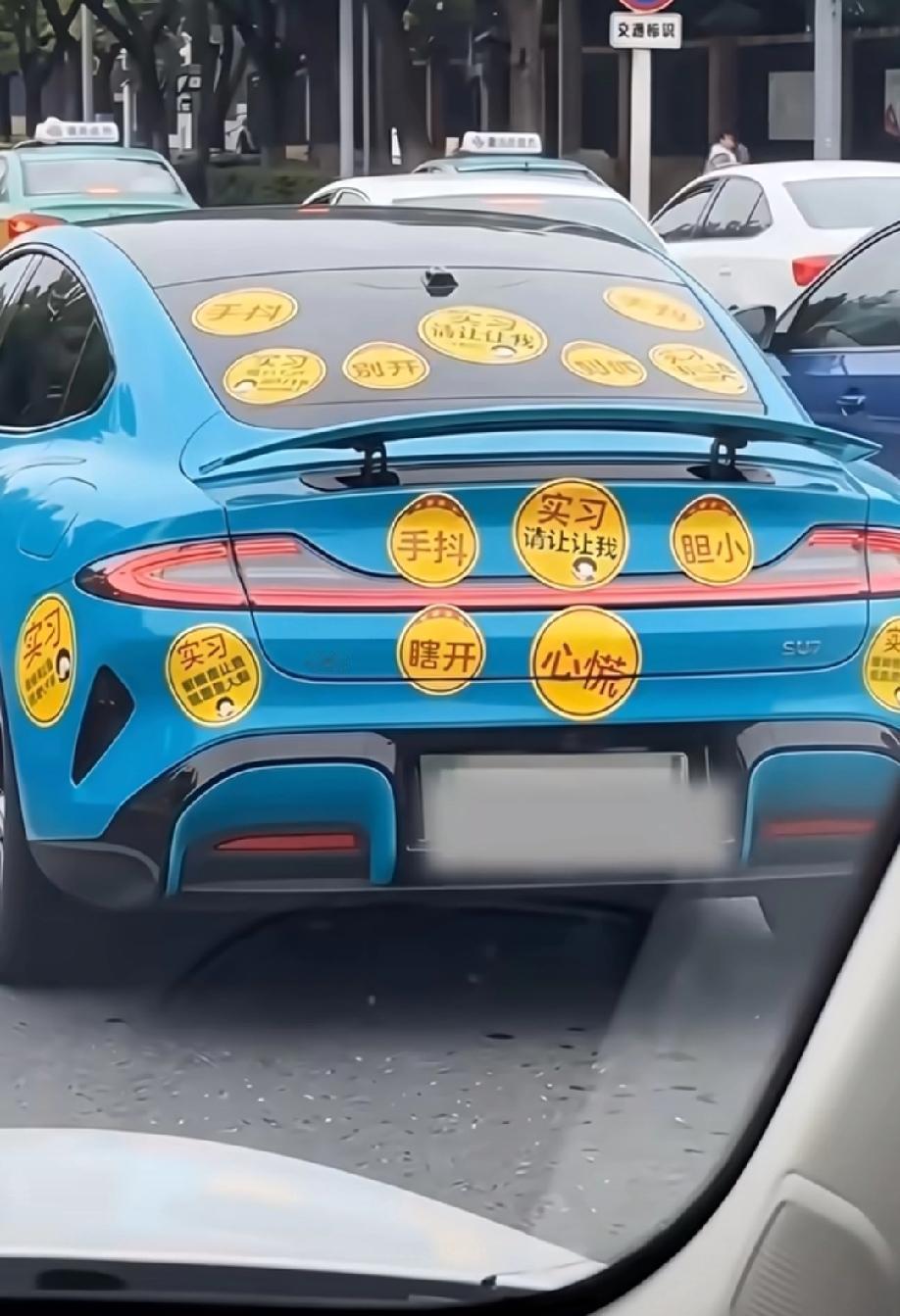 这位小米车主车身上贴满了“实习”、“手抖”、“心慌”的各种车贴。而后面这台问界也