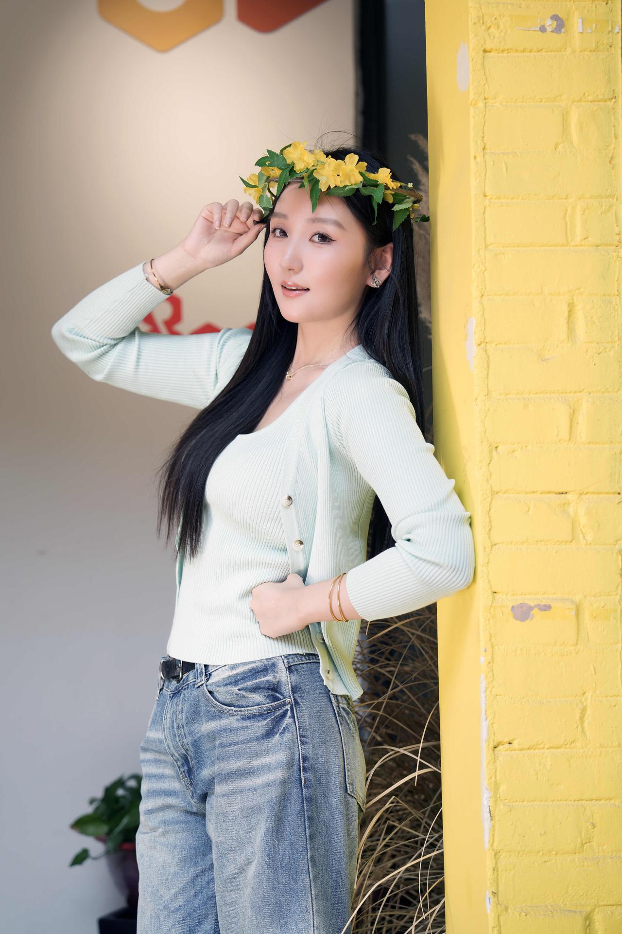 阳光明媚的午后，少女在黄色墙边轻抚发梢，花环点缀，自然清新。