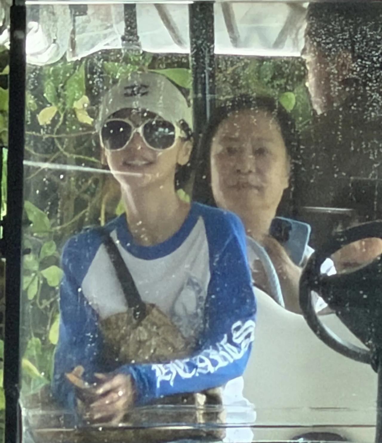 Angelababy带着爸爸妈妈，儿子小海绵在马尔代夫乘坐观光车，
穿蓝白T恤，