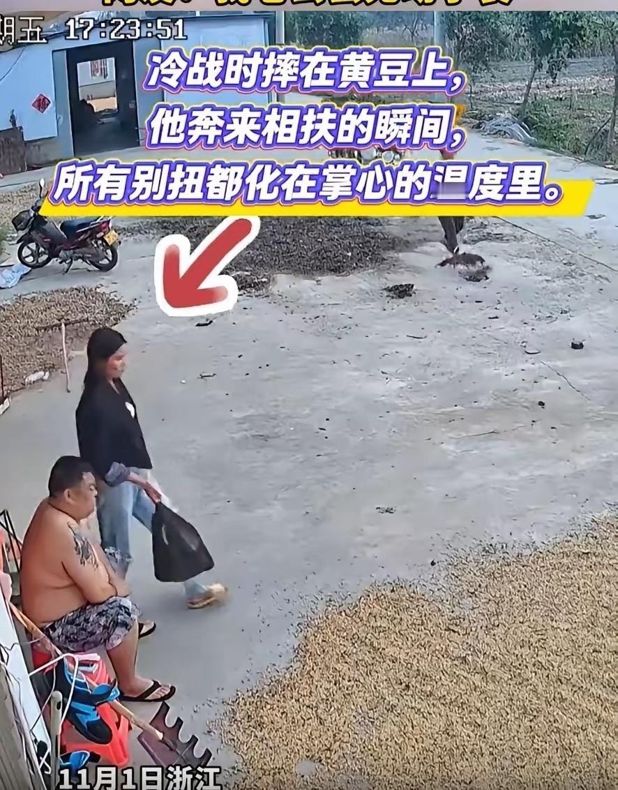 浙江一男子为使黄豆快点晾干，刚刚又耙了一遍。他有点累，坐在凳子上休息。
妻子提着