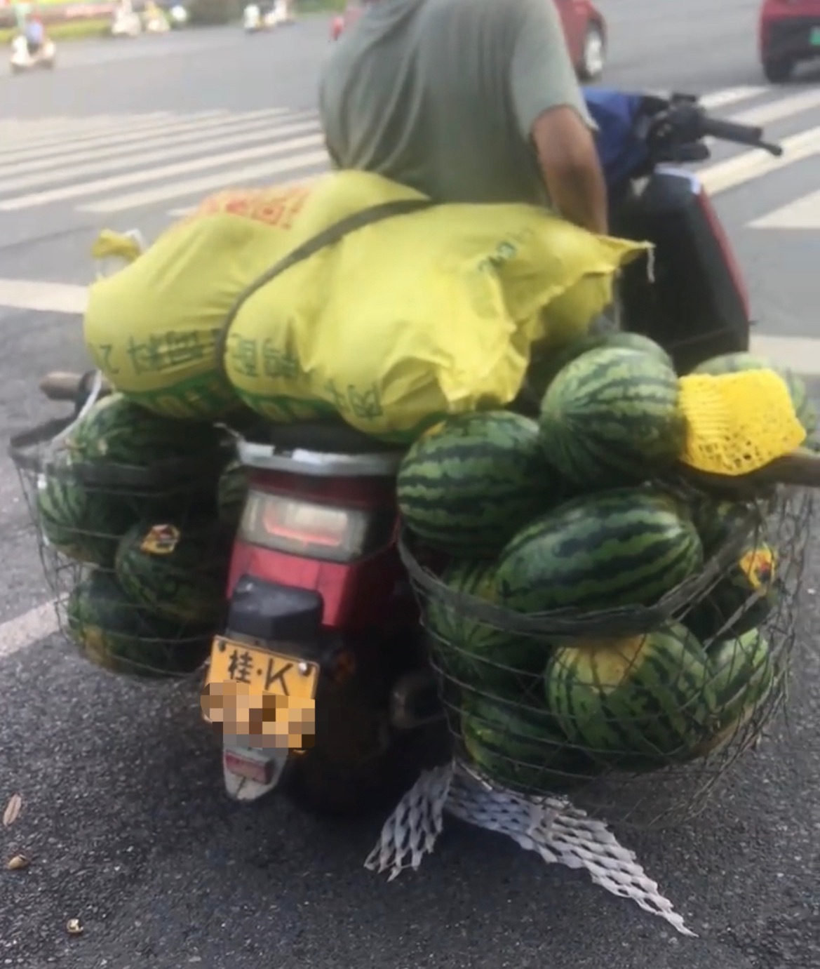 【玉林街头一男子骑两轮车载了数十个西瓜】6月30日，网友分享：玉林市街头看见一男