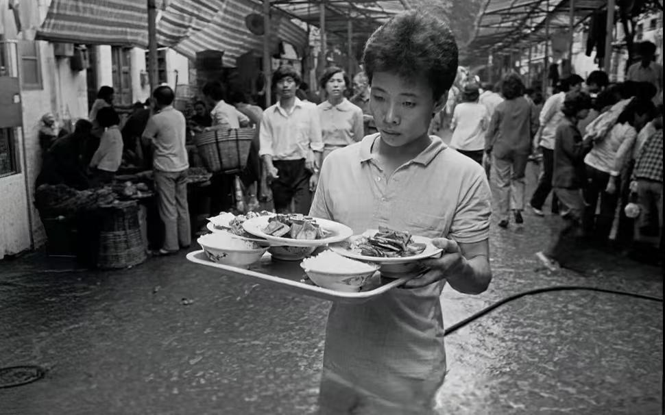 城市旧影里留存着往日鲜活的印记，上世纪八十年代，昔日广州荔湾清平市场一男子送外卖