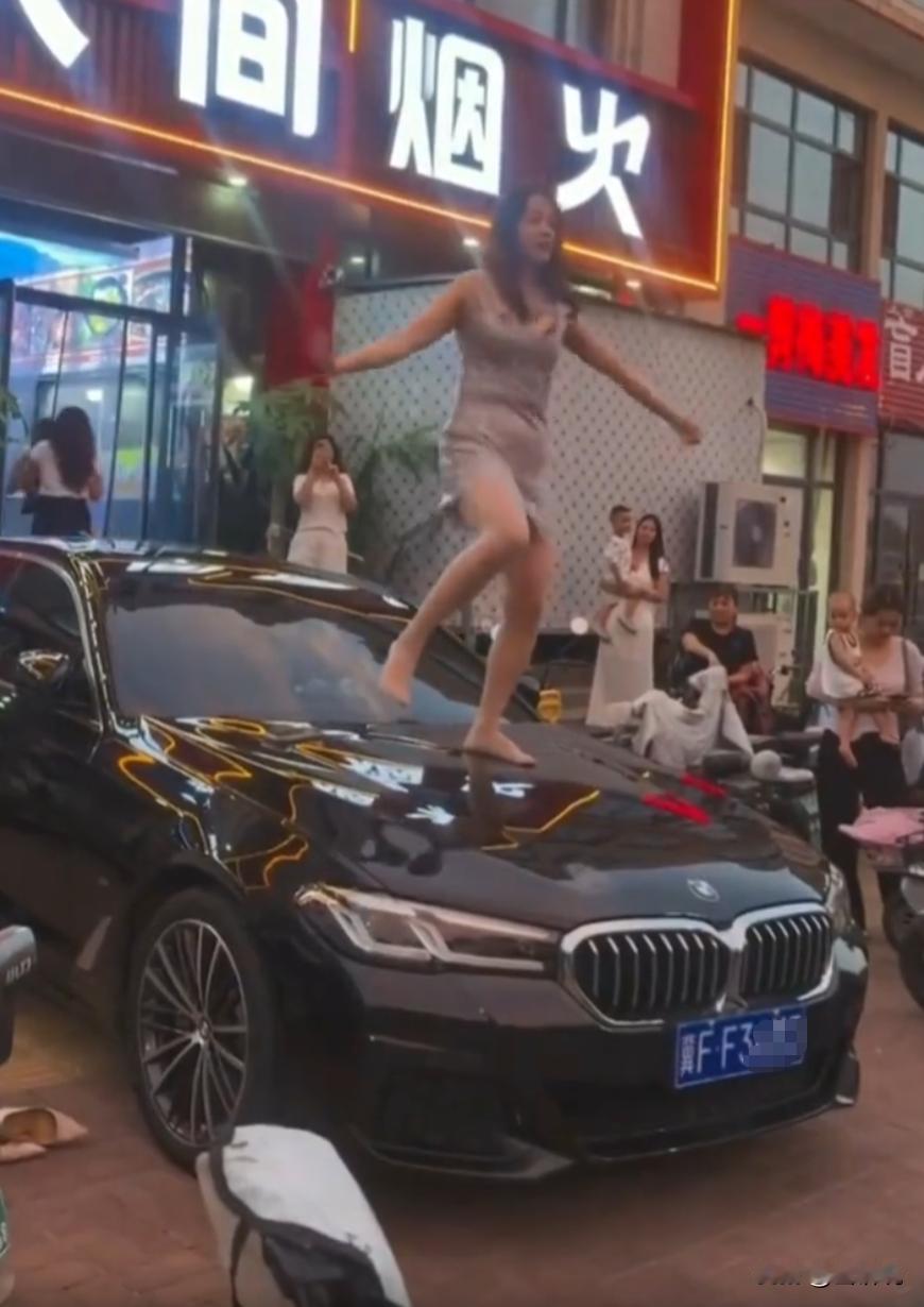河北保定，一名女子身穿吊带裙，直接站上路边宝马车引擎盖，在餐馆门口当众扭身热舞，