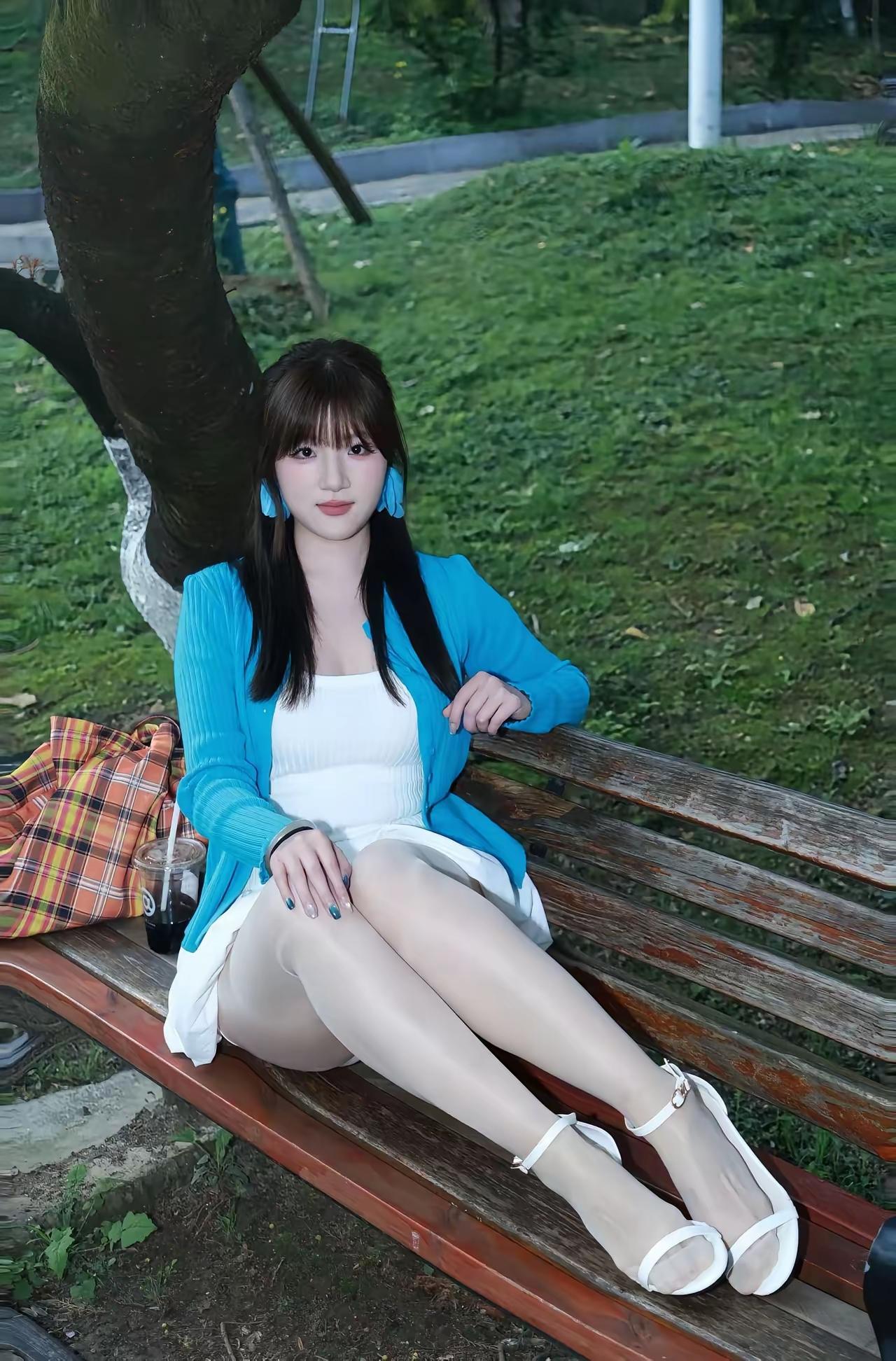 公园长椅上的甜美少女，蓝白相间的清新穿搭，享受宁静的午后时光。