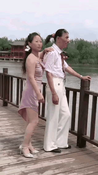 一男一女正在拍视频，男的岁数挺大，但是打扮挺新潮，穿着一身白衣，系个领带还扎个小