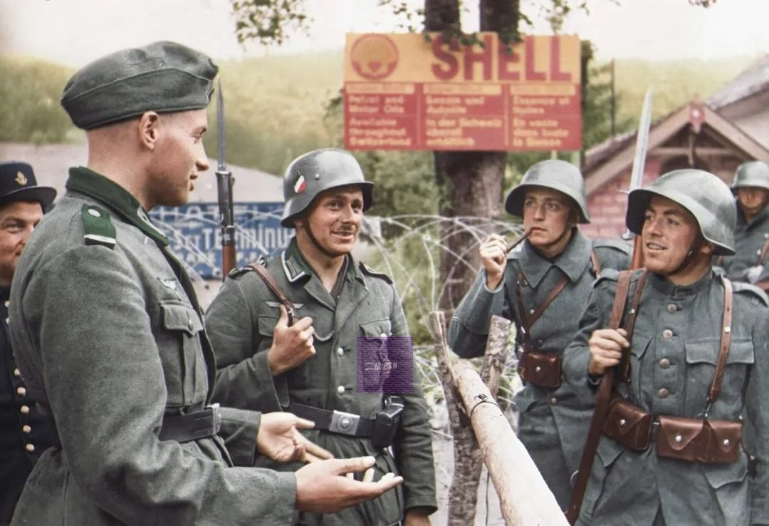 在1940年7月的法国蓬塔利耶，一名德国士兵正和一名瑞士士兵在边境交谈...