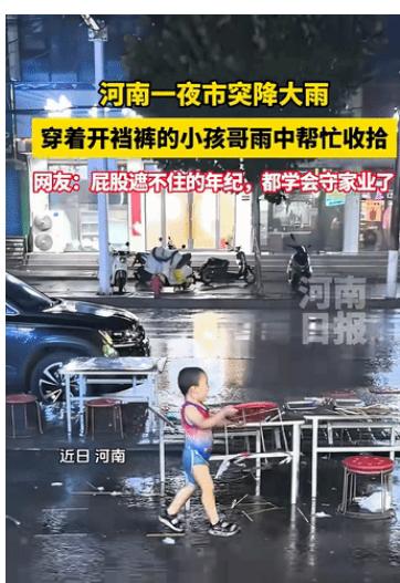 河南，一夜市突降大雨，眼见椅凳会被淋湿，这时一位穿着开裆裤的小男孩来来回回地在雨