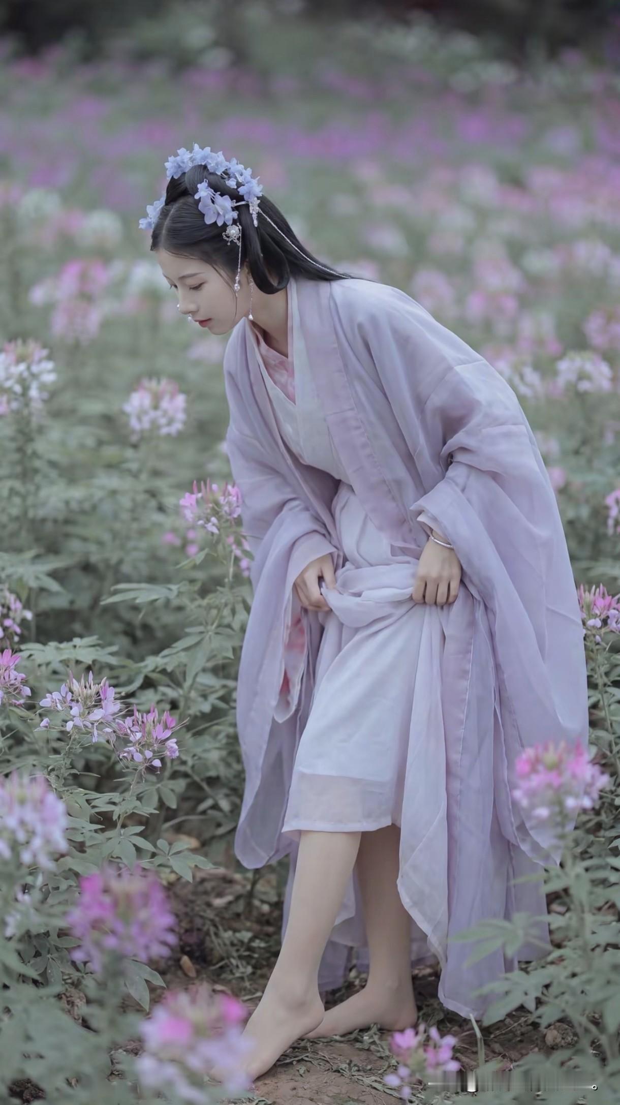 一袭淡紫汉服，手提竹篮，撑着油纸伞，
像是从古诗词里走出的采花女。
满园紫色花海