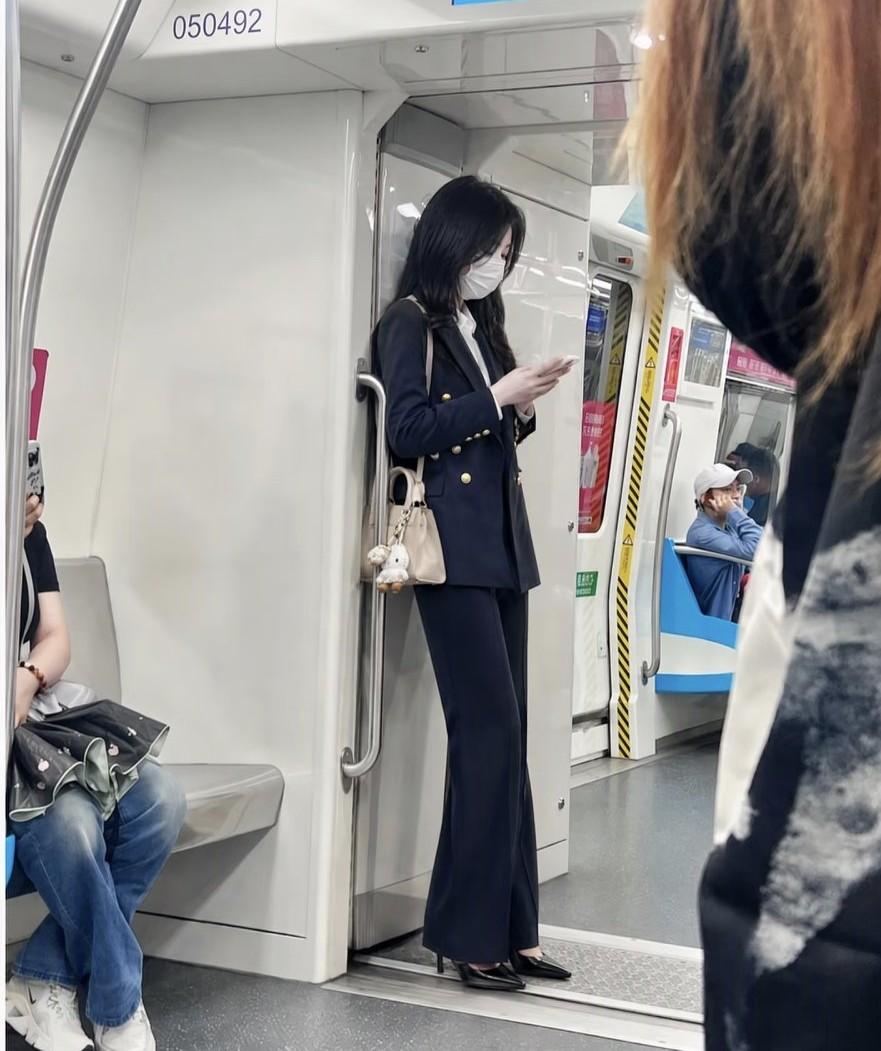  车厢人来人往，她独自靠着扶手，一身正装，自带不动声色的高级感。