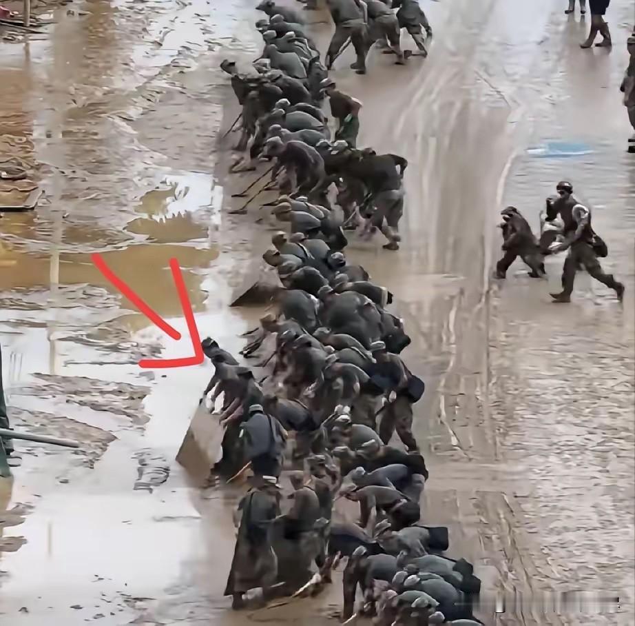 看到洪水退去后，战士们正吃力的清理着道路上的淤泥，清理这种残留在路面上的淤泥用推