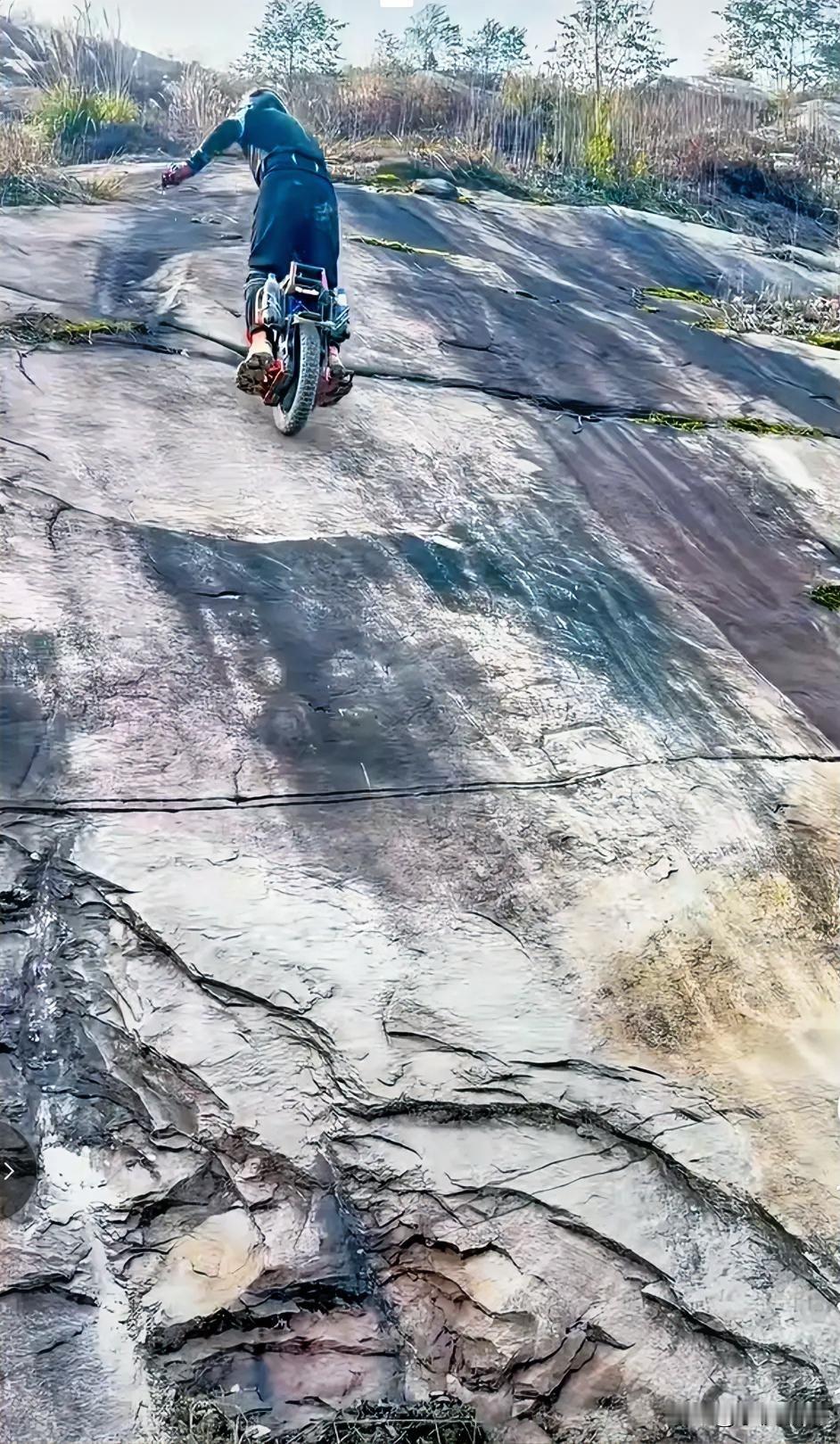 仅仅是带个了头盔，身上没有做任何安全防护，骑个独轮车就这样上了山体的崖壁。现在有