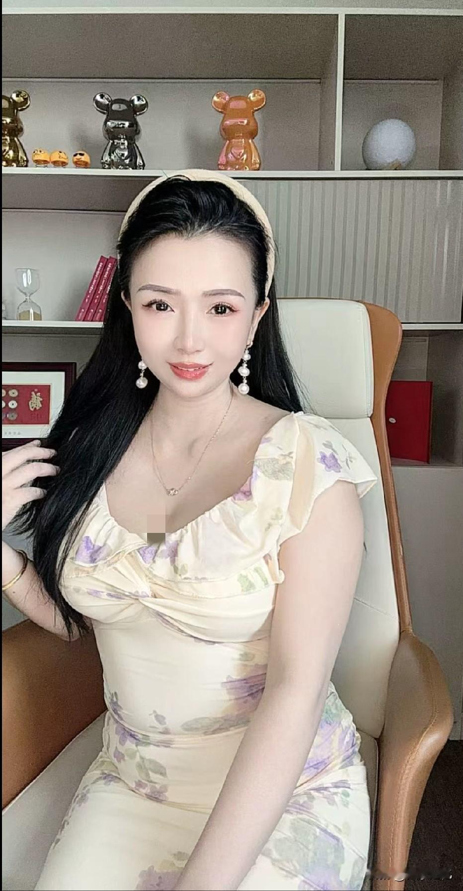 这位女士穿着花裙子，坐在椅子上。