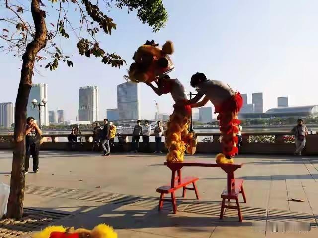 在热闹的街头巷尾，伴随着锣鼓声和鞭炮声，一对姐弟正专注地练习着舞狮的动作。姐姐1