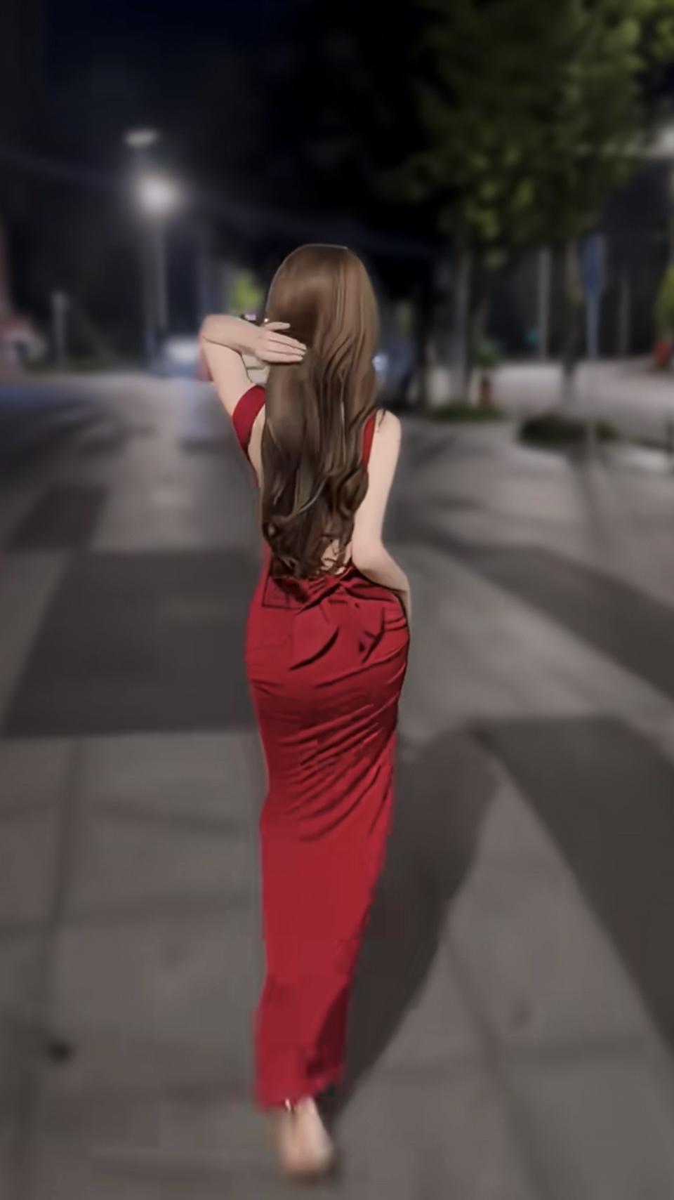 夜色里，一袭红裙似火焰在街头流动，长发随步伐轻扬，露背设计藏着精致巧思，每一步都