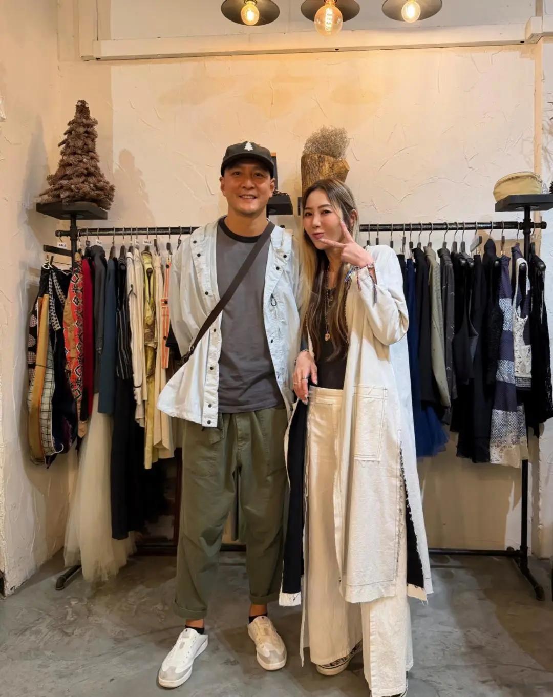 吴彦祖现身香港商店购物，他穿着一件白色外套，身材强壮，在买衣服时，和女粉丝合影，