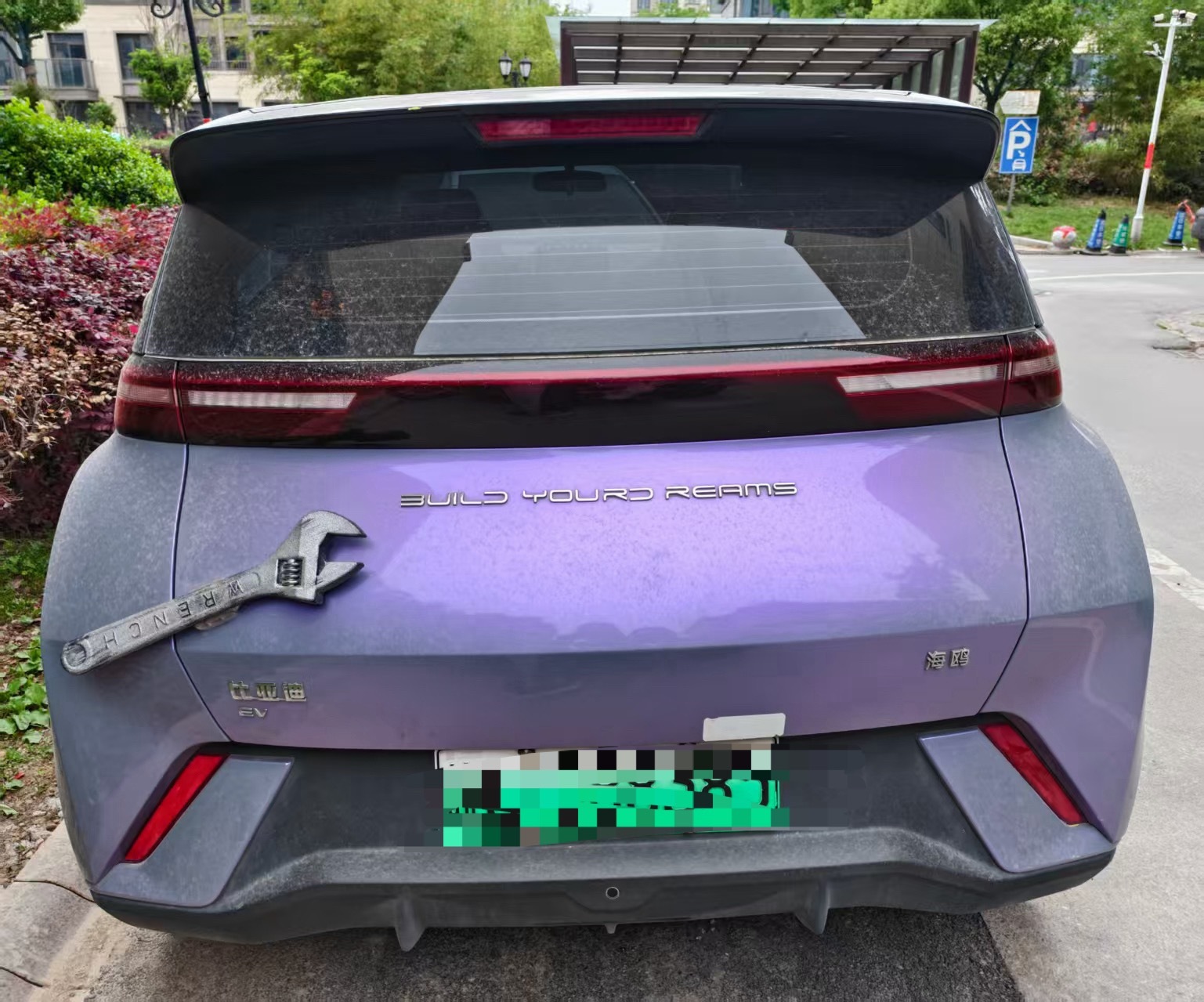 小区里看到的一辆比亚迪车屁股沾了一把扳手是啥意思
