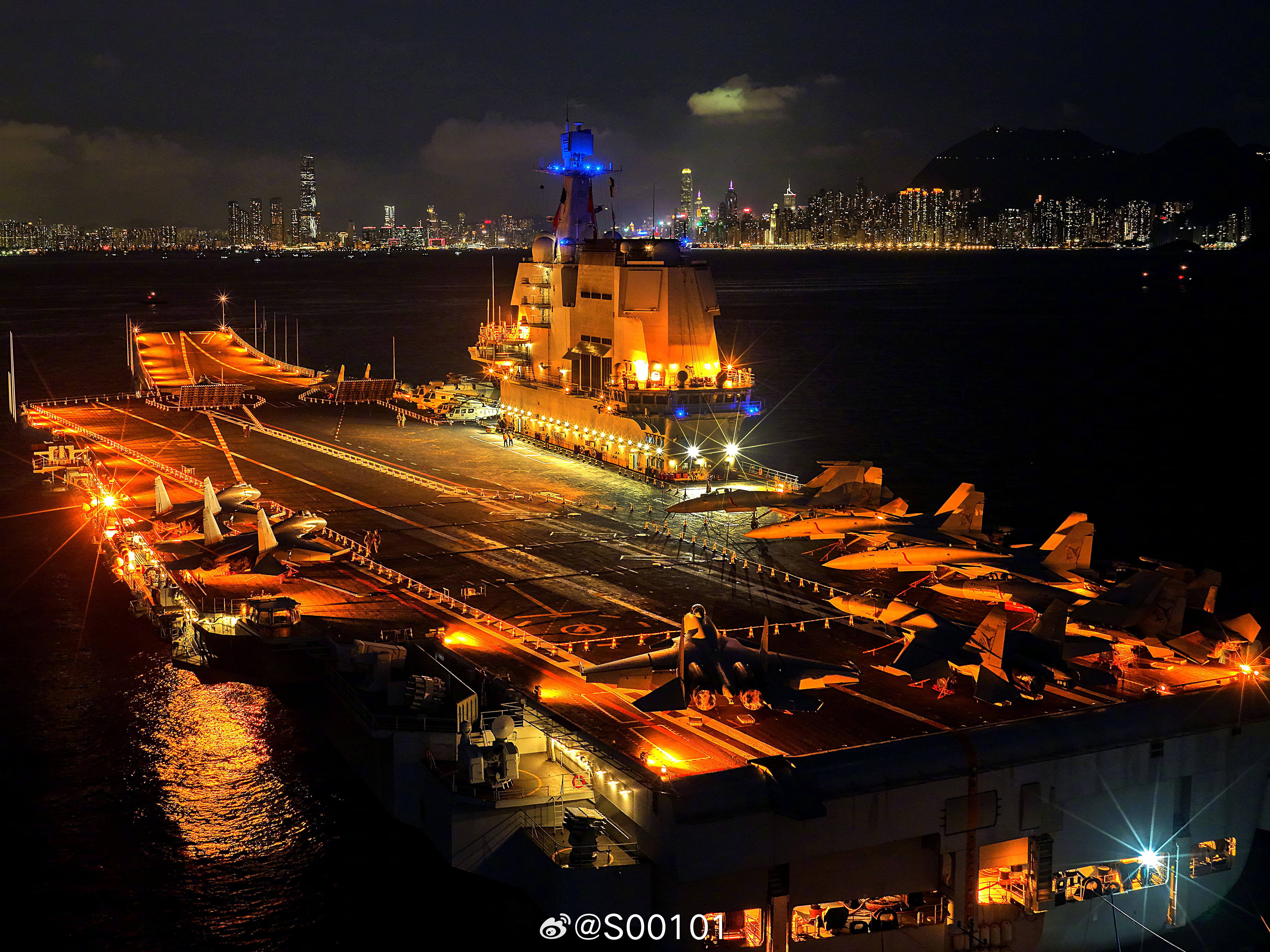 中国海军山东舰编队访问香港，夜幕降临在维多利亚港西锚地锚泊，舰艇灯光与城市霓虹交