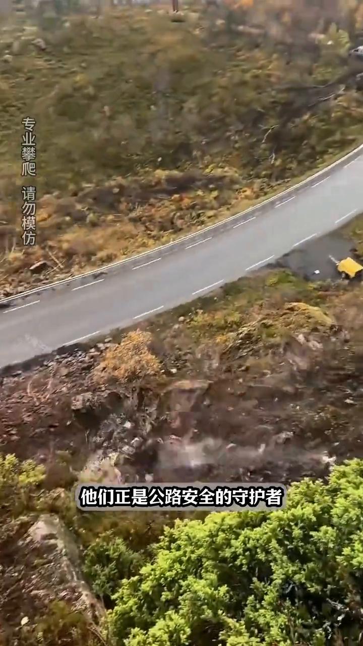 大家注意看，工人站在悬崖峭壁之上，利用专业工具将一块巨大的松动岩石从山体边缘推下