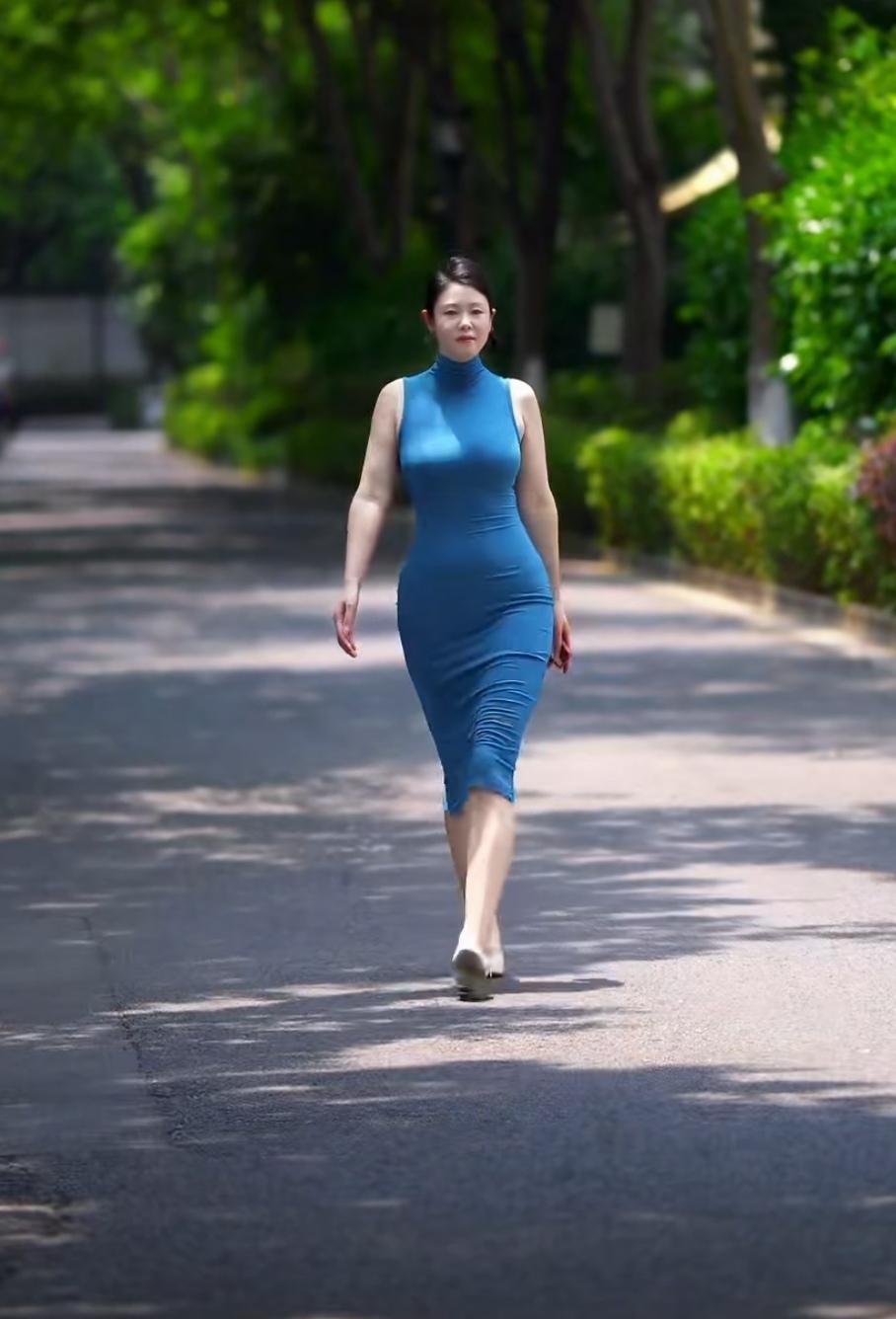 看到“优雅蓝裙女士，漫步绿荫道，自信步伐展风采”，就想起迪丽热巴南京雨中撑伞的出