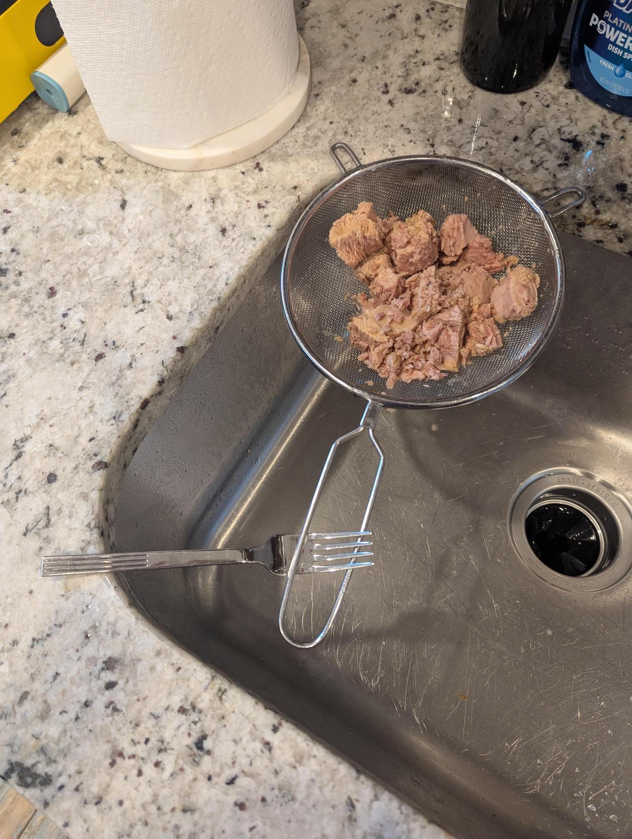 用叉子固定滤网沥干金枪鱼罐头，这个方法看似违反物理原理，实际上很稳定，类似达芬奇