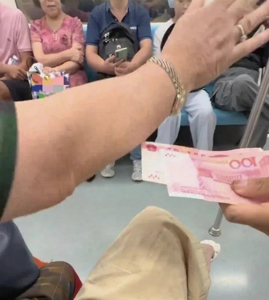 地铁上，一位男孩拿着500块现金，递给旁边的陌生奶奶，奶奶连忙摆手拒绝，并一把推