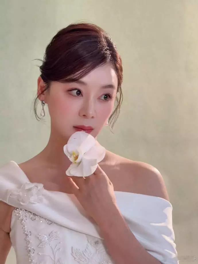 文亦娱乐袁姗姗盘发持花造型吸睛 白缎露肩礼服尽显温婉清雅 