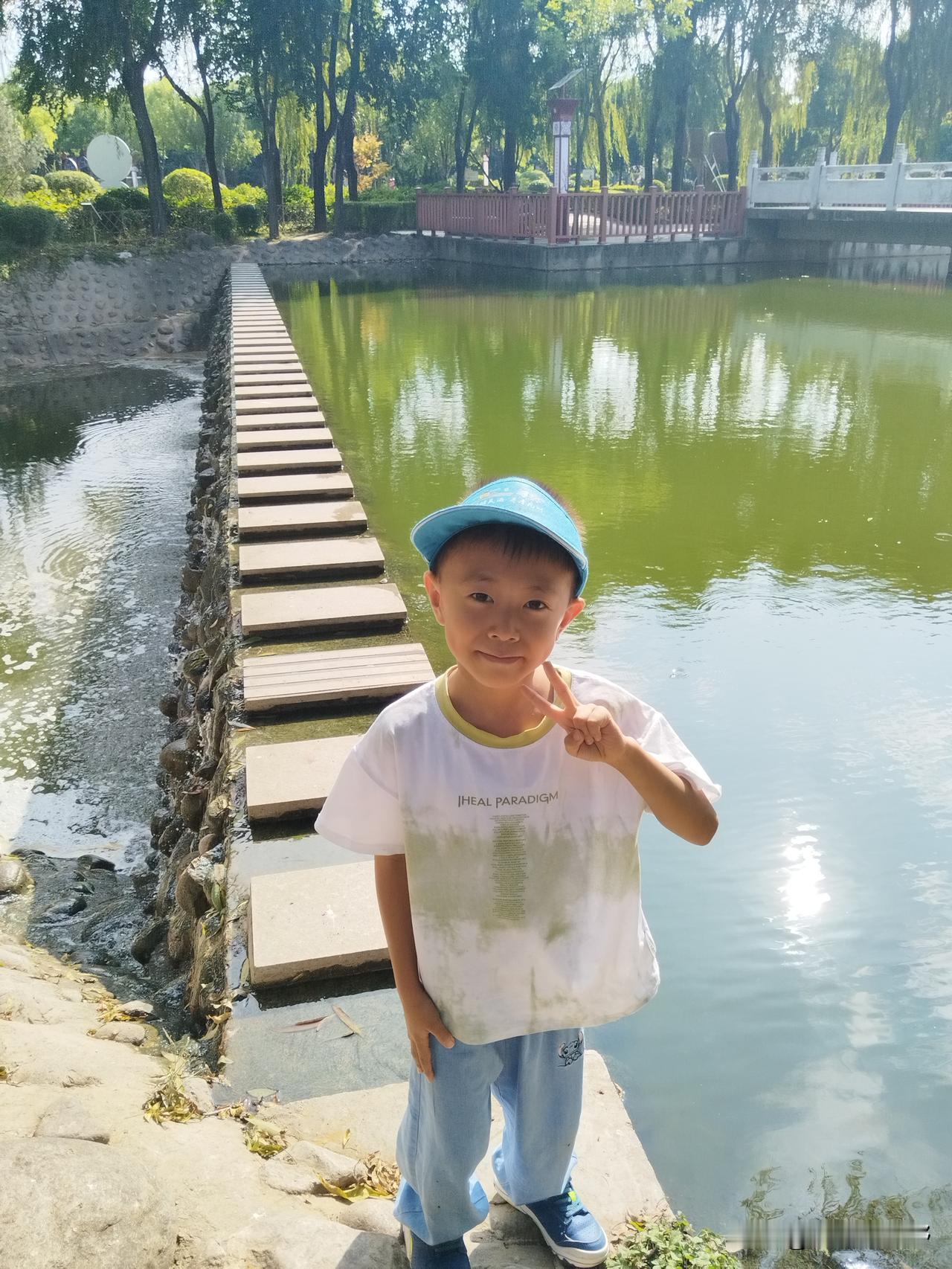 小家伙在湖边比着“V”字笑