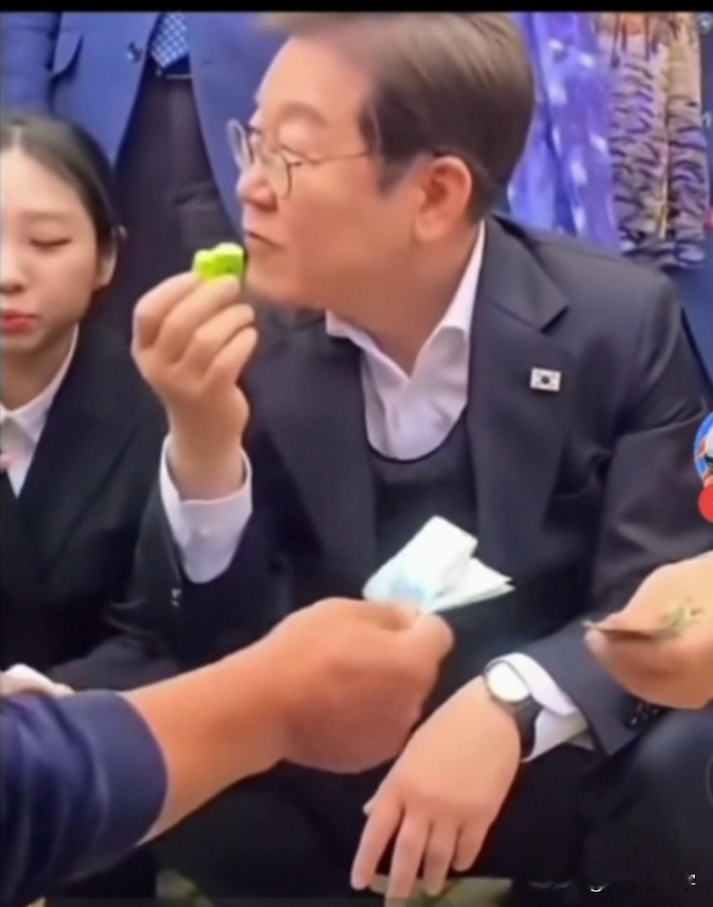 今天早上最大的收获是，李在明蹲在地下买地摊货，他黄瓜拿起一根黄瓜，用手抹了抹，然