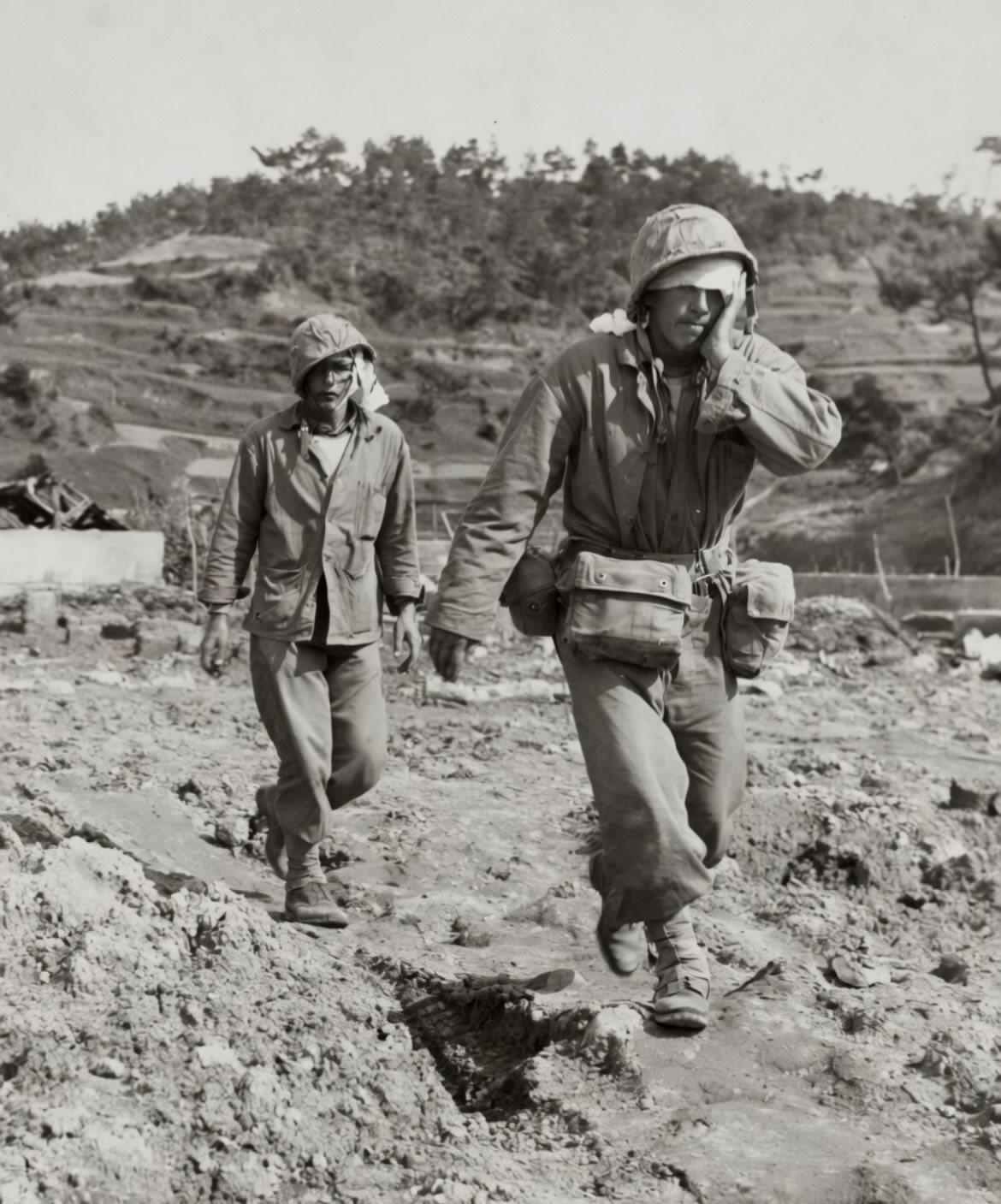 1945年冲绳的黑白照片：一名头部缠着绷带的美国海军陆战队员正抚摸着自己的伤口，