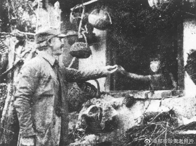 1938年，山西五台松岩口，白求恩大夫用樱桃逗村中女孩。 