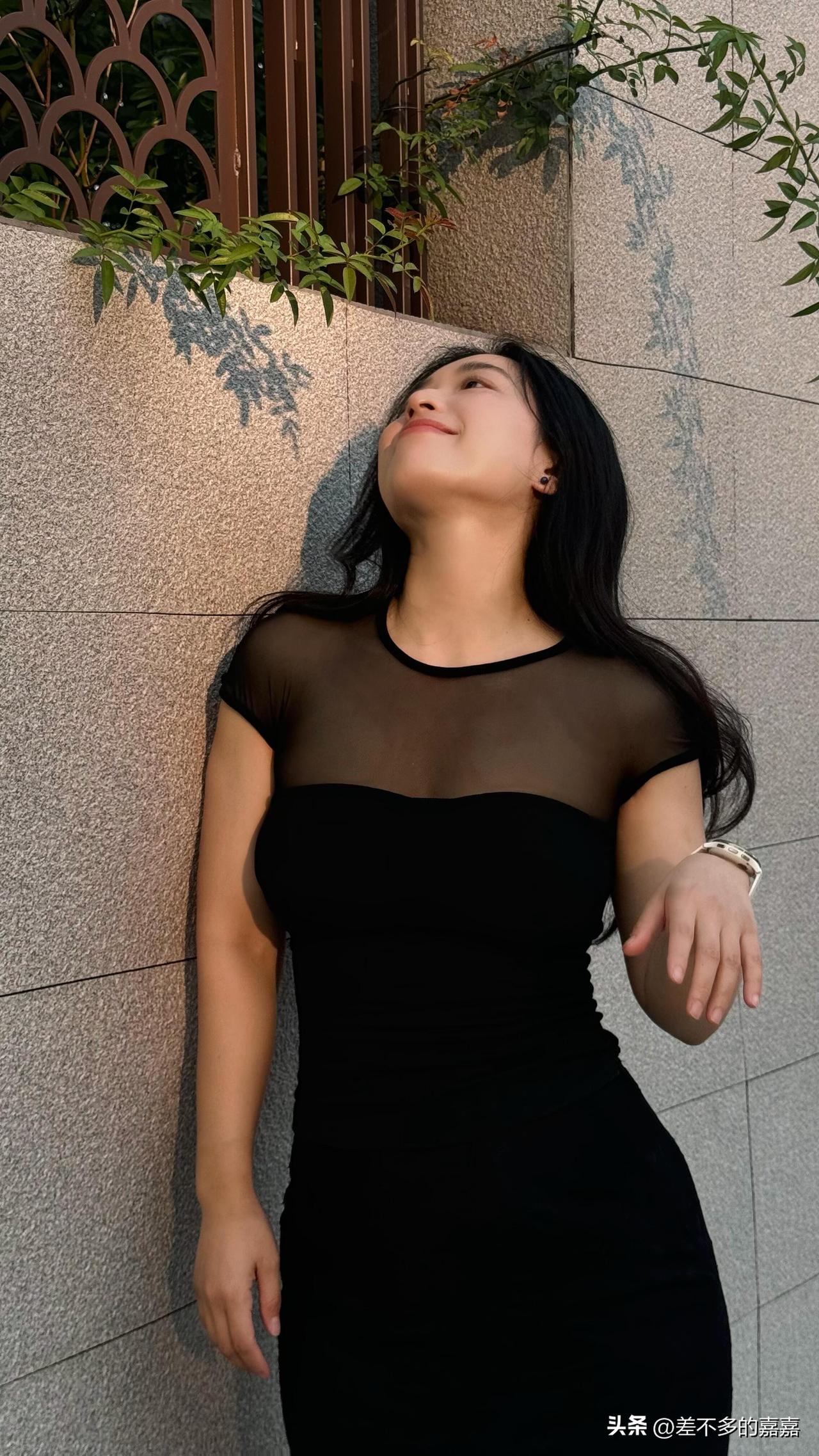 今天的黑色连衣裙，增添了几分性感与柔美，站在带有绿植投影的墙边，光影交错间，尽显