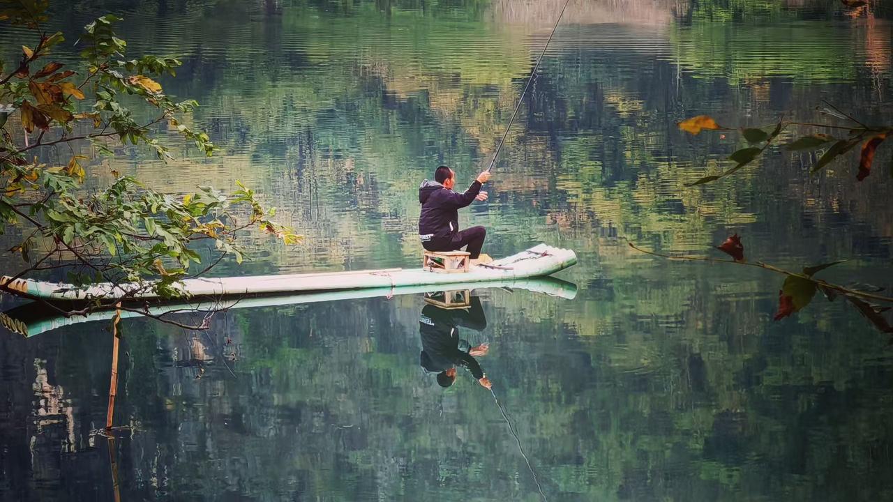 ✨水面铺展成翡翠色的绸，竹筏如叶浮在画里，钓线牵着的，是整个山野对静谧的、温柔的
