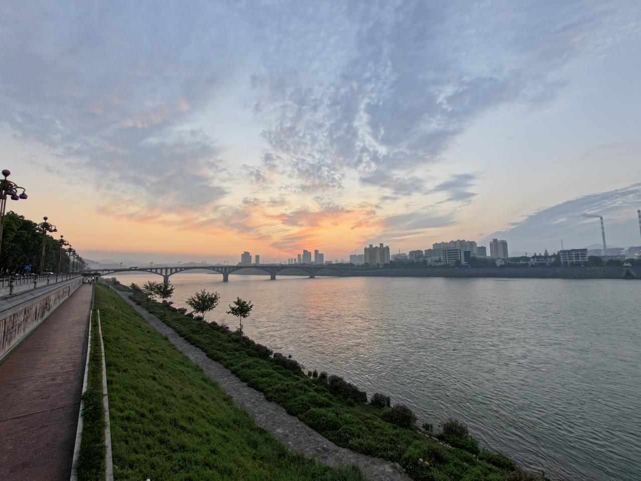 当朝霞漫过石门一桥，澧水便载着满河晨光，向东缓缓流去。
沿河大道的青草还沾着晨露